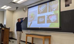 seminar speaker in front of a projector screen