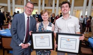 Three people, two holding award certificates