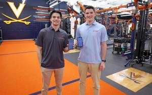 Two young men holding up cell phones in an athletic training facility at UVA