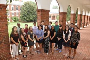 sixteen students standing for a picture on campus