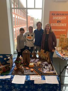 3 graduate students and PI in front of their gingerbread house entry for 2022.