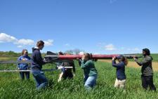 College student loading an 11.5-foot rocket on a launch rail